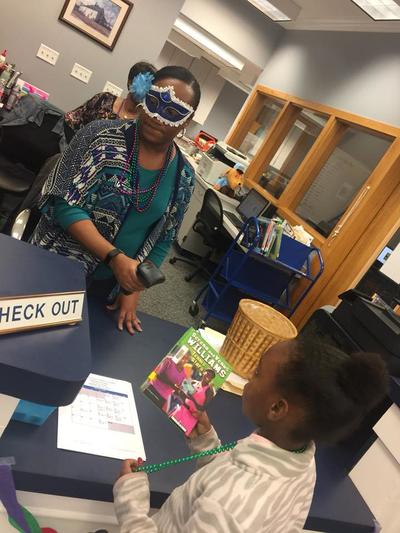 Girl Wearing Masquerade Mask at Book Checkout